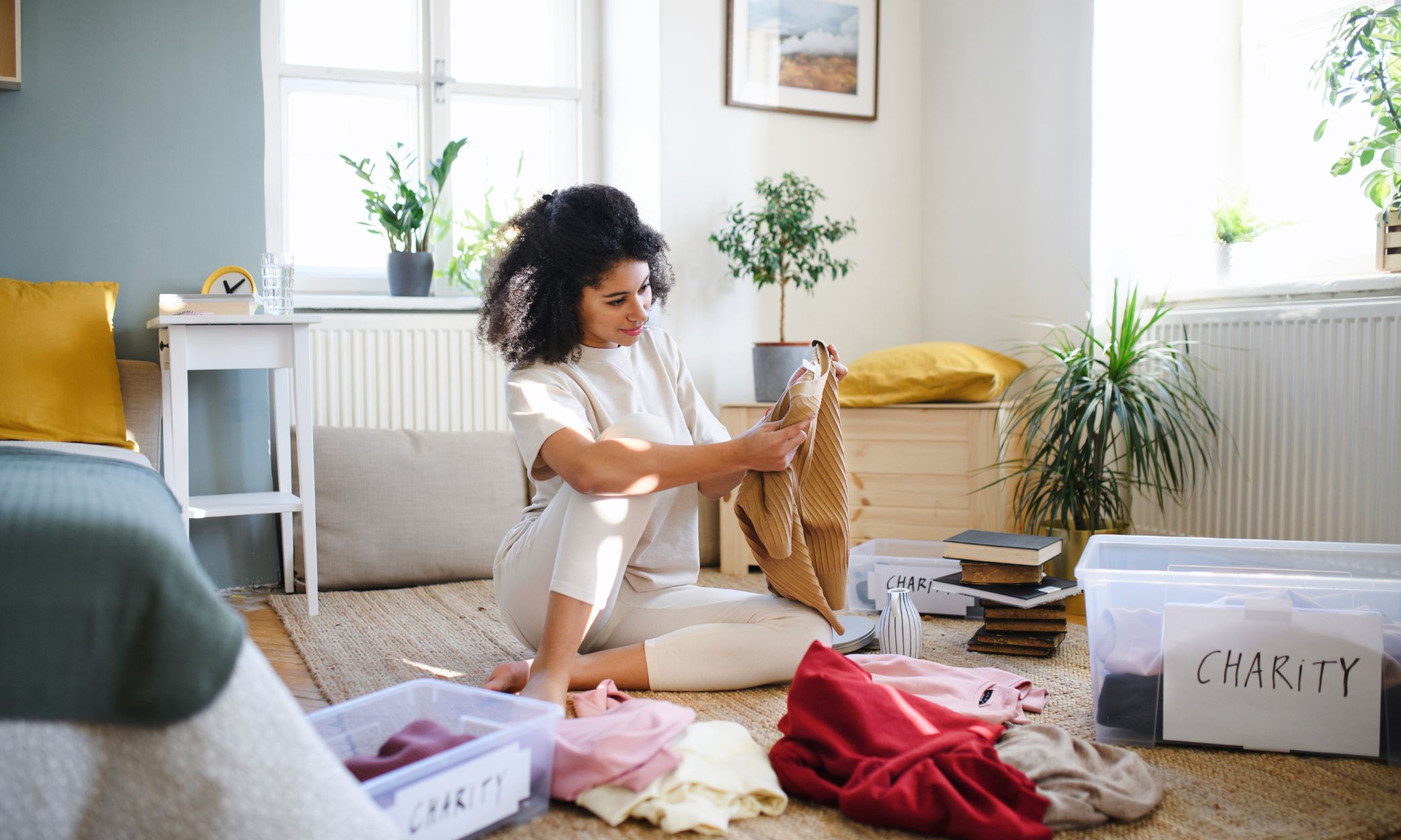 Lady sat on the floor sorting through clothes and items to declutter her home